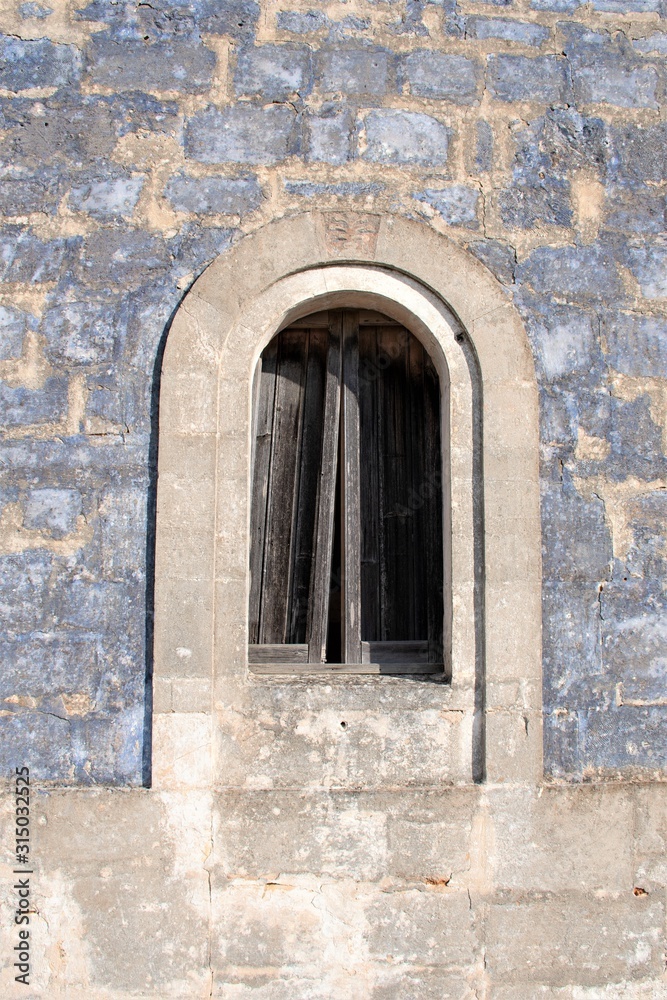 Ancient stone window of an old stone house in a countryside village in Puglia, Italy, Europe, vertical