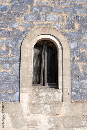 Ancient stone window of an old stone house in a countryside village in Puglia  Italy  Europe  vertical