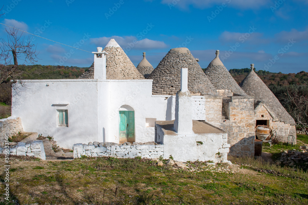 Group of Trulli with garden, traditional old houses and old stone wall in Puglia, Italy, Europe