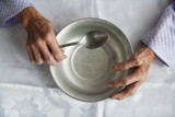 View from above.The hands of an old grandmother of 90 years are holding an empty aluminum bowl and spoon, poverty and poverty, the hunger of the older generation.