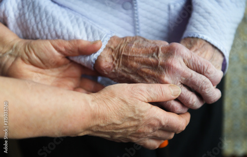 Hands of a mature wife or guardian holding the hands of her elderly woman or patient, as an expression of care and support.Close up photo of a dedicated caregiver holding an elderly woman's hands