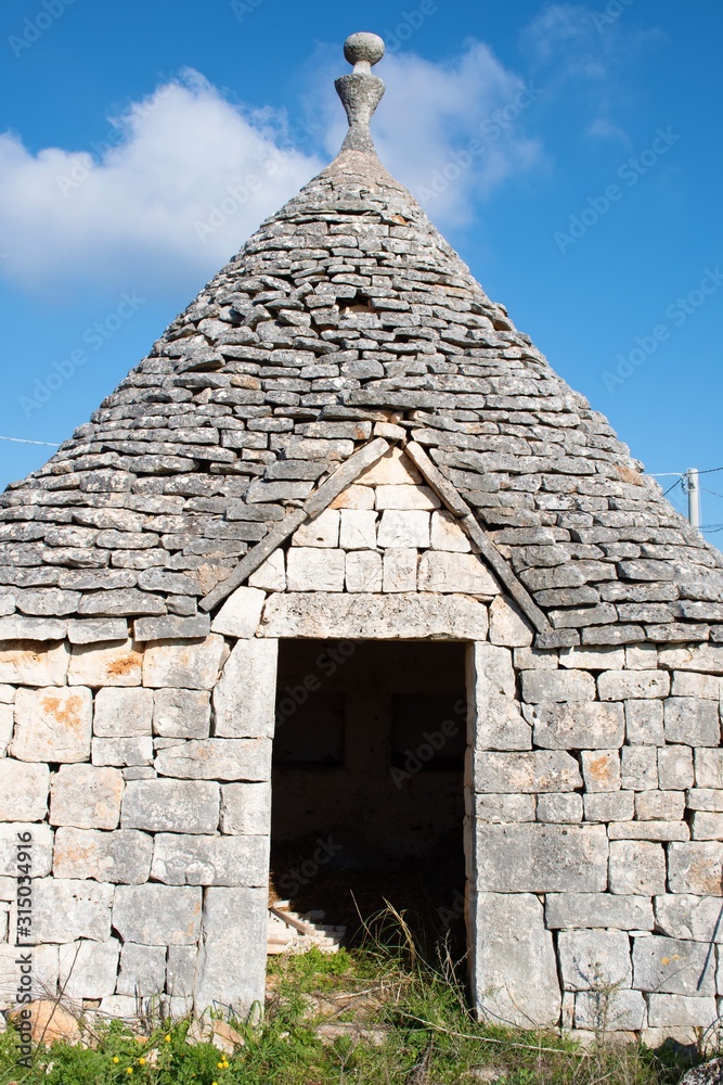 Tullo with door, traditional old house and old stone wall in Puglia, Italy, Europe, vertical