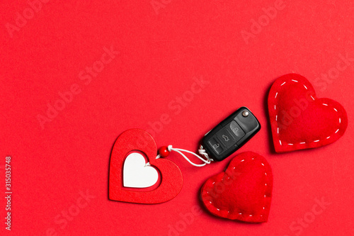 Top view of car key, wooden and textile heart on colorful background. Luxury present for Valentine's day