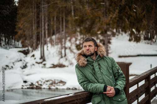 Happy bearded man in a green jacket walking in a forrest, outdoor, outfit, shoes, winter look, adventure, hiking