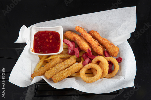 Snack platter - French fries,  spring rolls, fried sausage, chicken nugget, Turkish pastry, onion rings, potato croquette on plate. photo