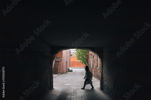 Silhouette of a young girl in an old arch. The concept of walking, loneliness, tourism, slums and poverty. © shchus