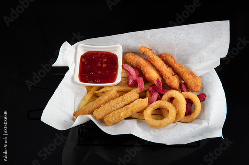 Snack platter - French fries,  spring rolls, fried sausage, chicken nugget, Turkish pastry, onion rings, potato croquette on plate. photo