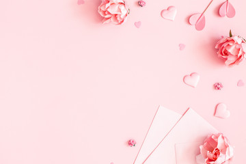 Valentine's Day background. Pink flowers, envelope, hearts on pastel pink background. Valentines day concept. Flat lay, top view, copy space