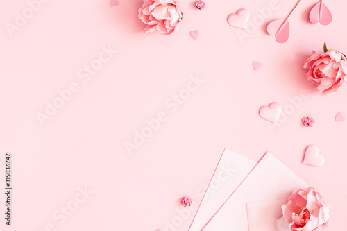 Valentine's Day background. Pink flowers, envelope, hearts on pastel pink background. Valentines day concept. Flat lay, top view, copy space