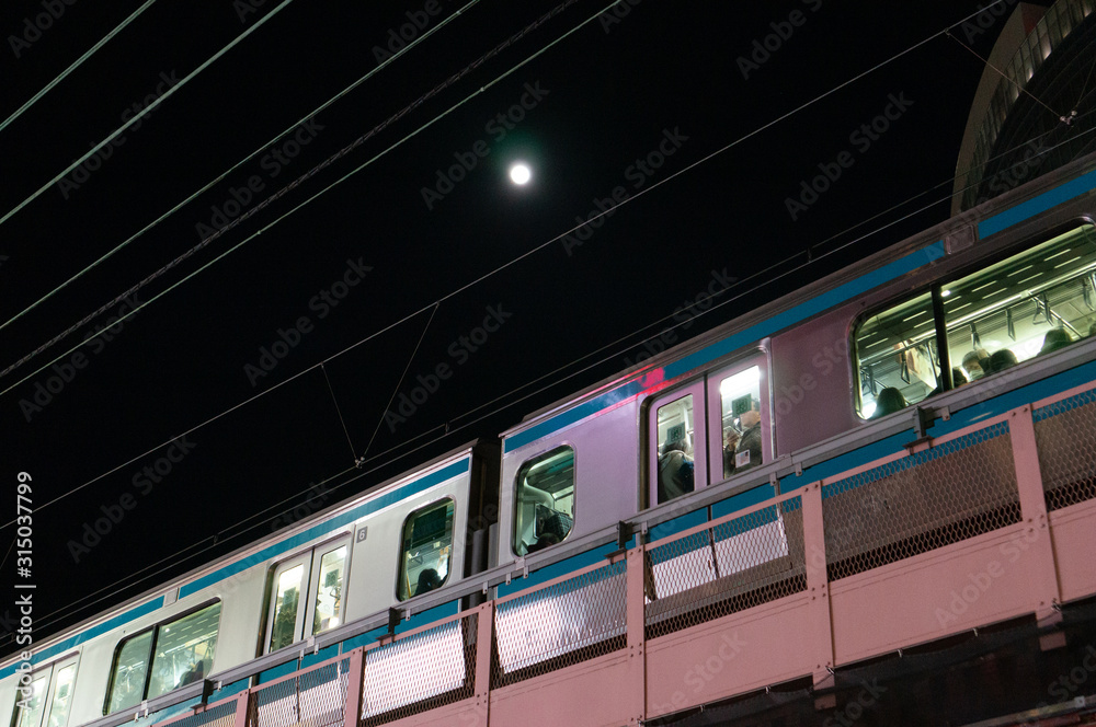 Obraz premium 東京、帰宅ラッシュ時の混雑した電車と月