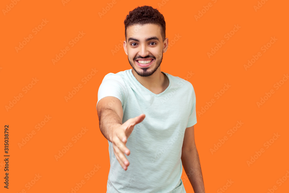 Φωτογραφία Portrait of friendly positive handsome brunette man with beard in casual white t-shirt giving hand to handshake, welcoming and getting acquainted