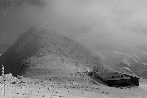 Bad weather on Stone cottage on the peak of Chopok mountain in Low tatras in Slovakia. Big fog is coming. Windstorm with fog is created lethal combination. Very depressing atmosphera photo