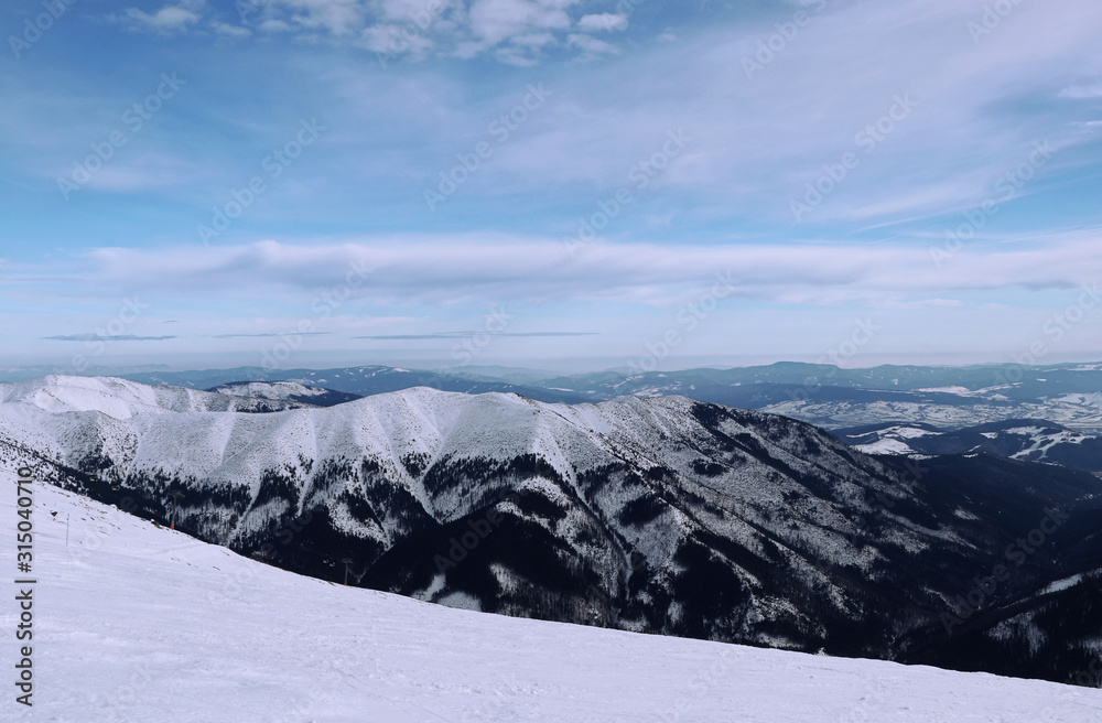 View on Vajskovska and Jasenianska valley from Chopok mountain in Low Tatras, Slovakia. Fairy-tale landscape with many snowy hills and sky with many shadows of blue. Paradise same as in Alps