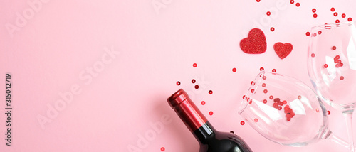 Valentines day dinner concept. Top view table setting for romantic dinner with bottle of wine champagne and two glasses on pink. Valentines day celebration, love, romantic dinner couple concept