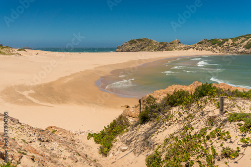 Vast sandy beach with sand dunes and rocks and cliffs