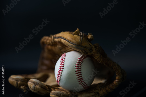 Photography Baseball in a glove on black background.