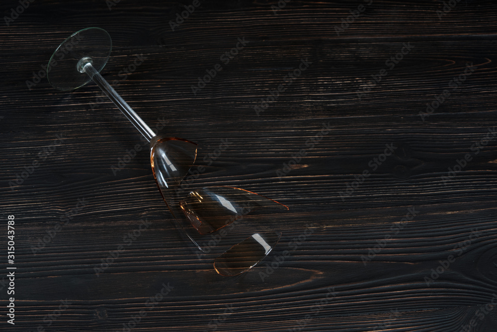 Broken glass for wine on a dark wooden table Broken glass for wine on a dark wooden table