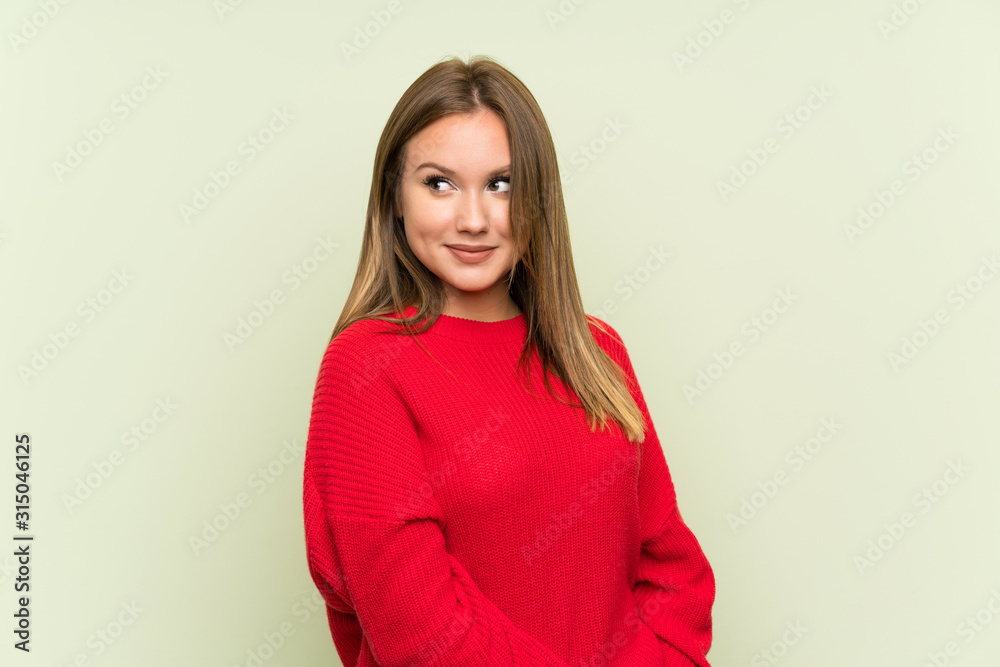 Teenager girl over isolated green background standing and looking to the side Teenager girl over isolated green background standing and looking to the side