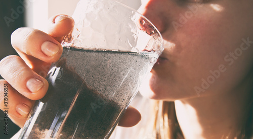 The woman is drinking  dirty water from the glass cup