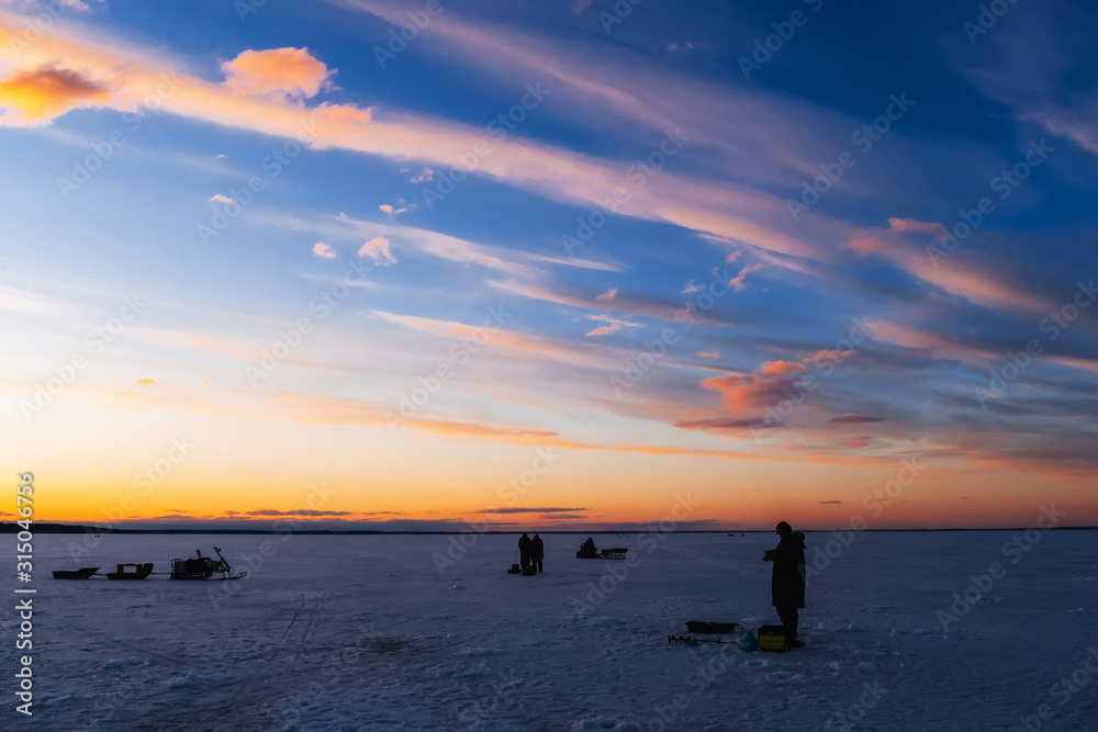 silhouettes of a fisherman with a fishing rod on a winter fishing