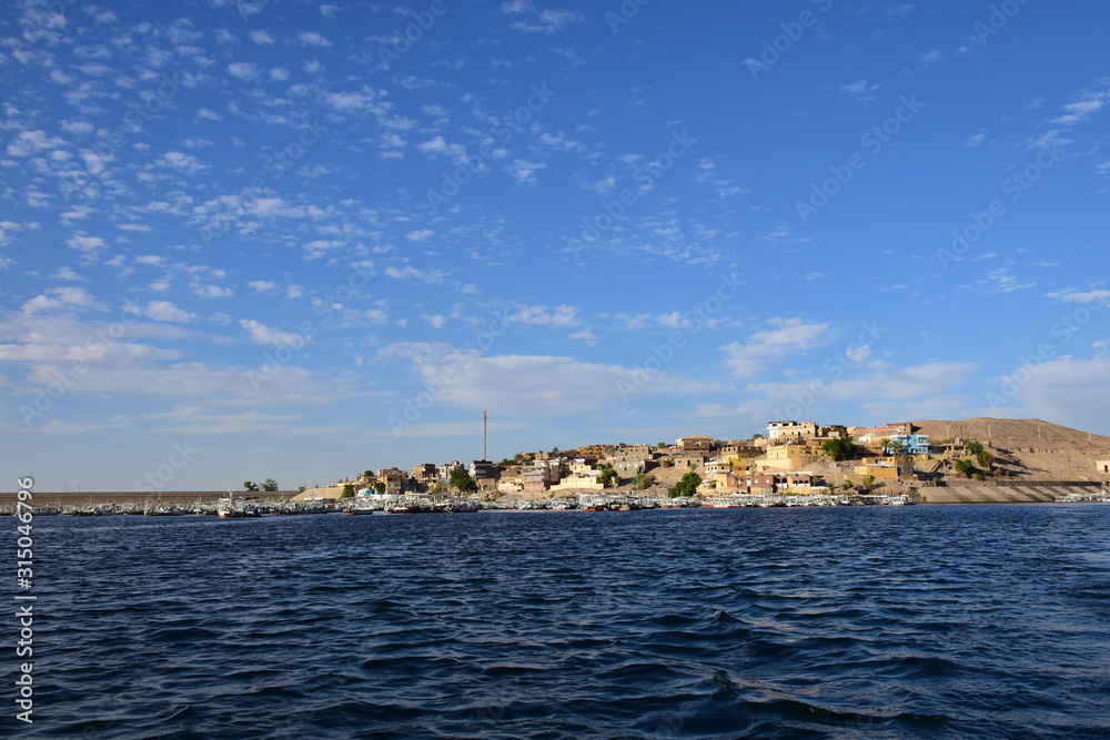 Fototapeta premium River Nile/ beautiful view for Aswan Egypt and Nubian Egyptian culture. sailing boat sailing in the River Nile and harbor with birds and local houses on the 2 sides 