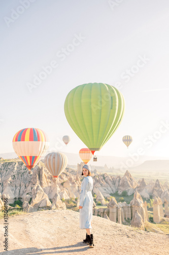 Beautiful woman watching colorful hot air balloons flying over the valley at Cappadocia, Turkey Cappadocia fairytale scenery of mountains