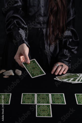 Female tells the future with playing cards. Tarot card concept on the table. Prediction of the future. Fortuneteller hands in black vestments.Psychic.