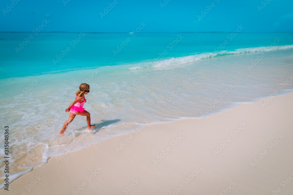 happy cute little girl run and play with waves on beach