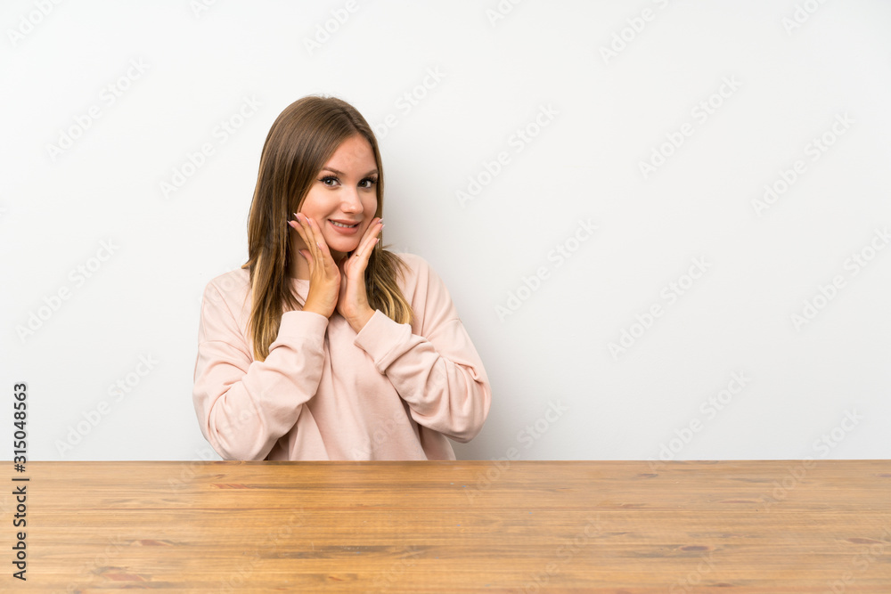 Teenager girl in a table with surprise facial expression Teenager girl in a table with surprise facial expression