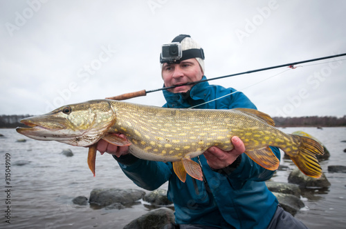 Angler with pike fishing trophy on Swedish coast