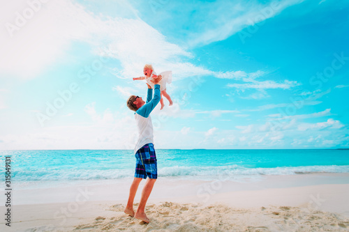 father and cute little daughter play at beach