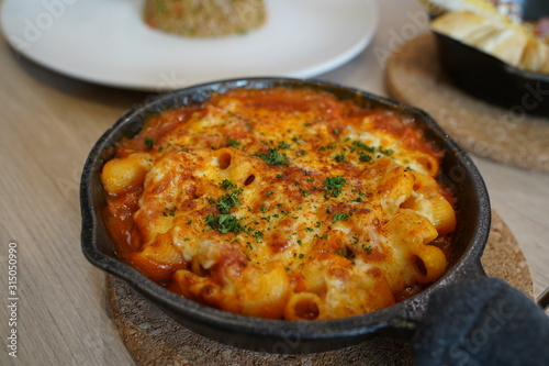Macaroni mixed with cheese and tomato sauce served on pan.