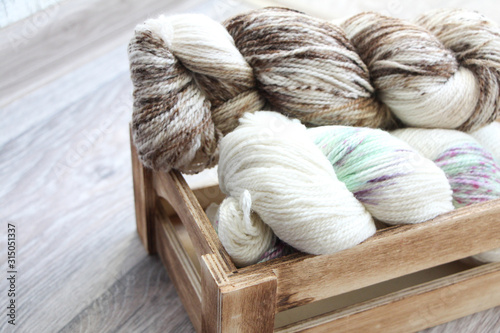 Two skeins of multicolored yarn in a wooden box