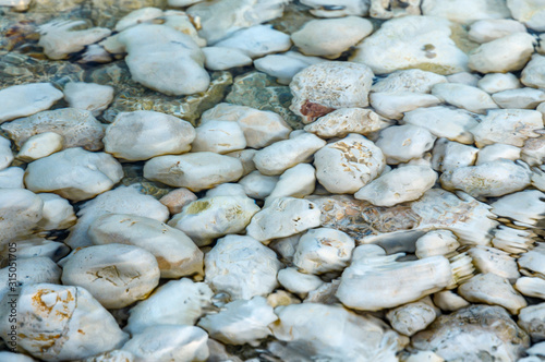 Abstract background texture, Colorful sea stones in water. Wonderful natural background. Clear crystal shallow blue sea water and rocky seabed background, banner.