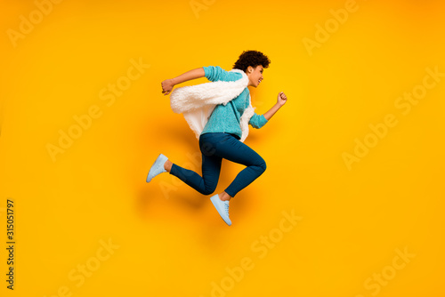 Full size profile side photo crazy beautiful afro american girl jump run hurry discounts wear teal sweater stylish trendy white blue pants trousers sneakers isolated yellow color background
