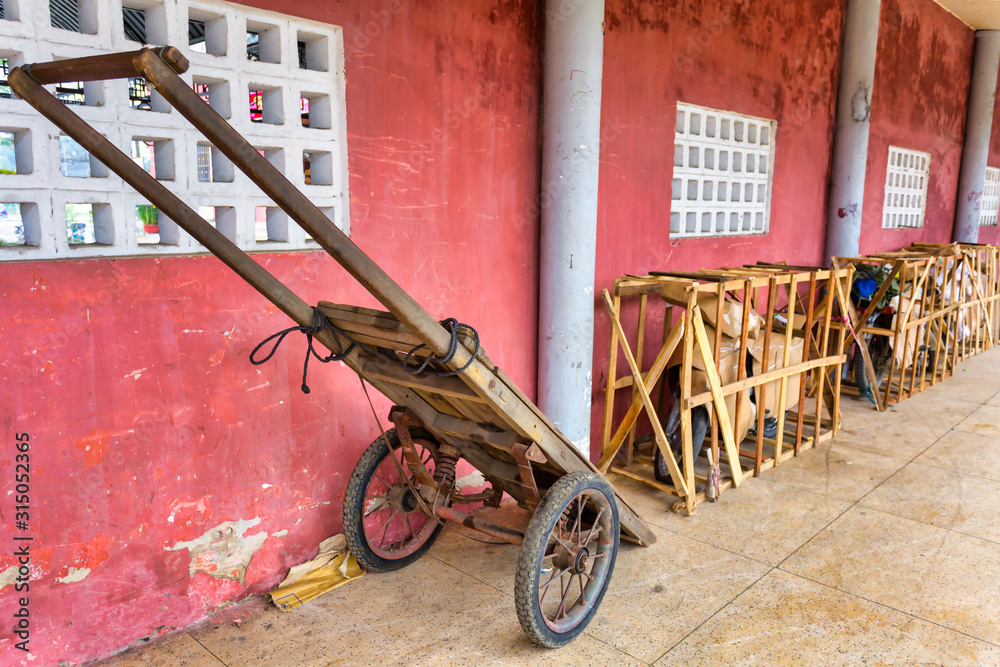 Fototapeta premium Vietnamese motorbike transport service. Bikes are fixed in wooden frames covered with cardboard, wheelbarrow on the foreground. Hue train station, Vietnam