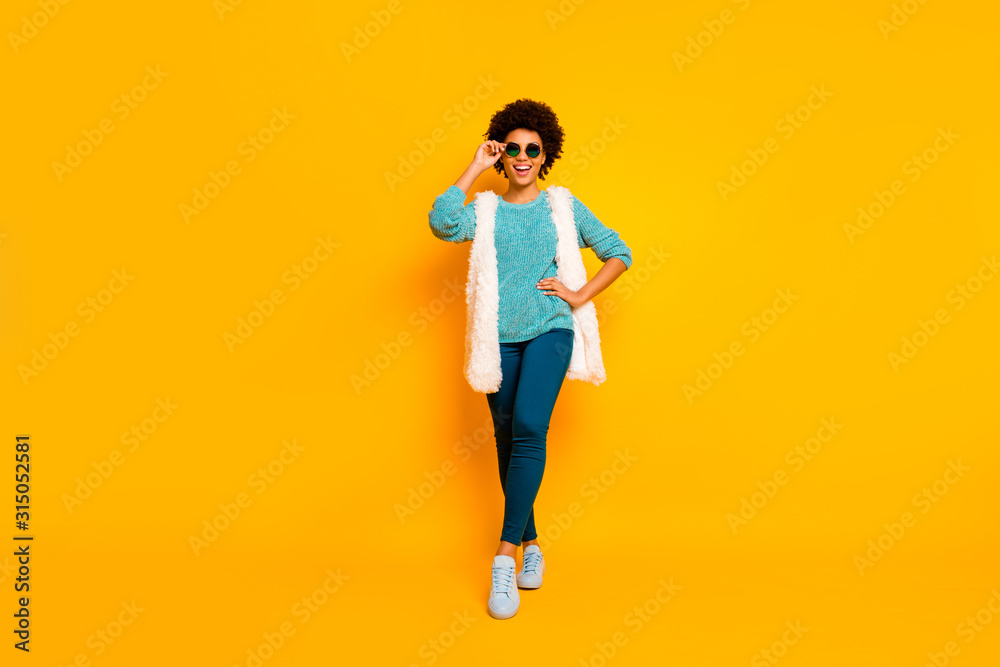 Full size photo of cute positive funky afro american girl enjoy autumn holiday touch spectacles wear white stylish trendy waistcoat blue pants isolated bright color background Full size photo of cute positive funky afro american girl enjoy autumn holiday touch spectacles wear white stylish trendy waistcoat blue pants isolated bright color background