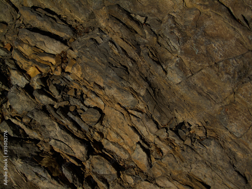 Dark brown stone background. Mountain texture. Close-up. Abstract grunge background. Rock formation texture. Rocky surface backdrop.