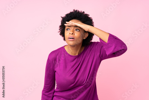 African american woman over isolated pink background looking far away with hand to look something