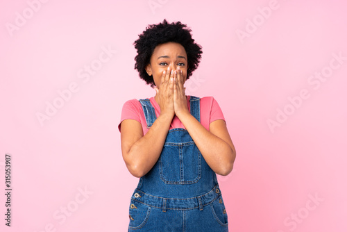 African american woman with overalls over isolated pink background with surprise facial expression