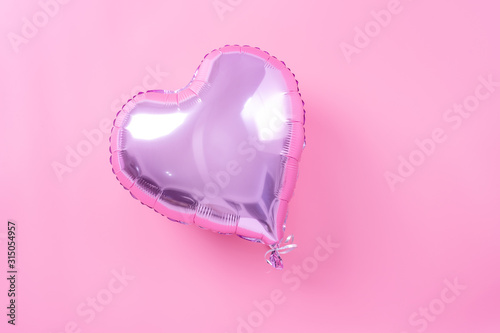 Valentine's Day minimal design concept - Beautiful real heart shape foil balloon isolated on pale pink background, top view, flat lay, overhead above photography.