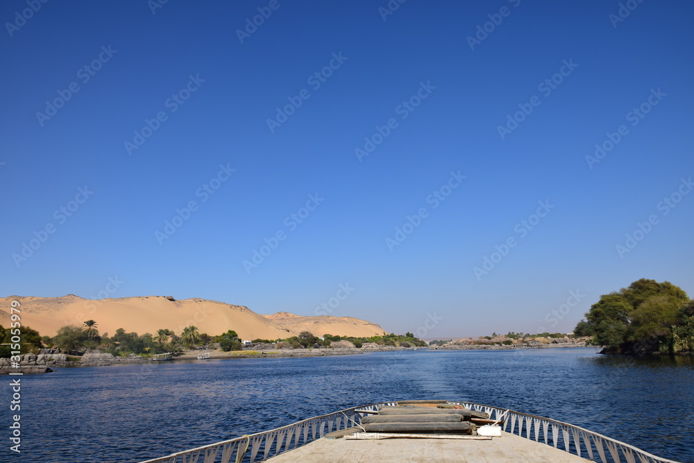 River Nile/ beautiful view for Aswan Egypt and Nubian Egyptian culture. sailing boat sailing in the River Nile and harbor with birds and local houses on the 2 sides 