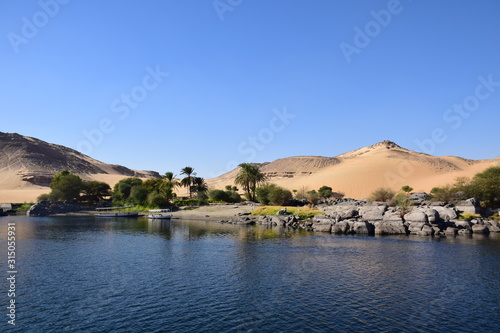 River Nile/ beautiful view for Aswan Egypt and Nubian Egyptian culture. sailing boat sailing in the River Nile and harbor with birds and local houses on the 2 sides 