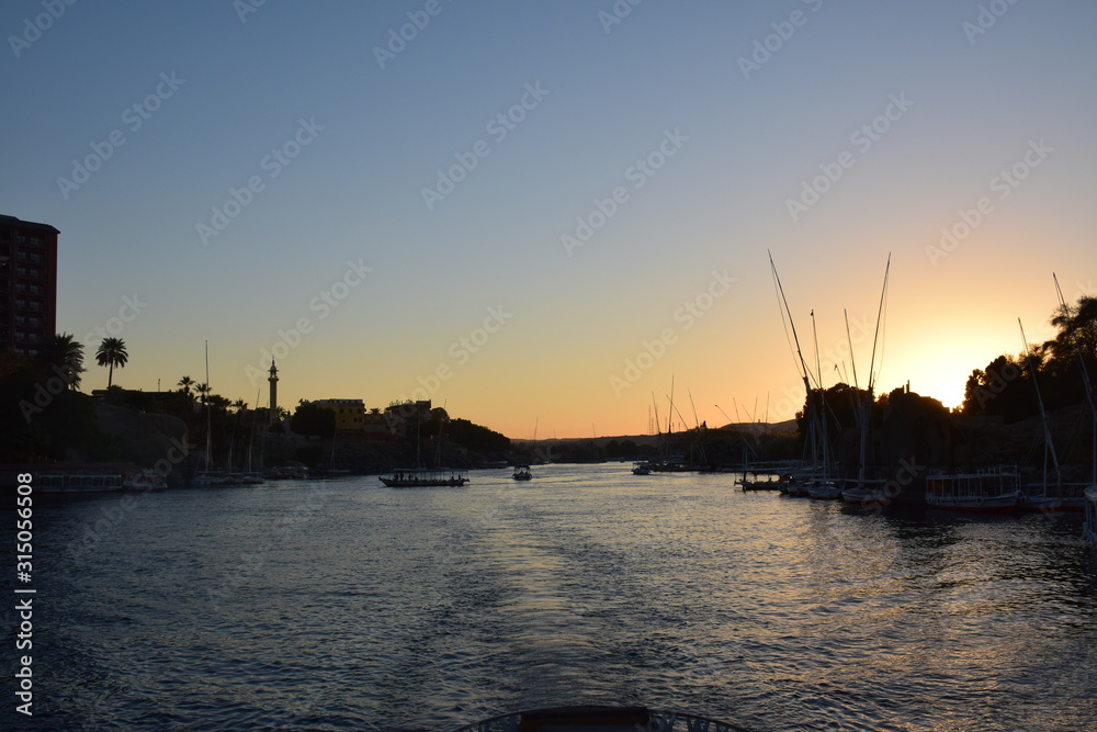 River Nile/ beautiful view for Aswan Egypt and Nubian Egyptian culture. sailing boat sailing in the River Nile and harbor with birds and local houses on the 2 sides 