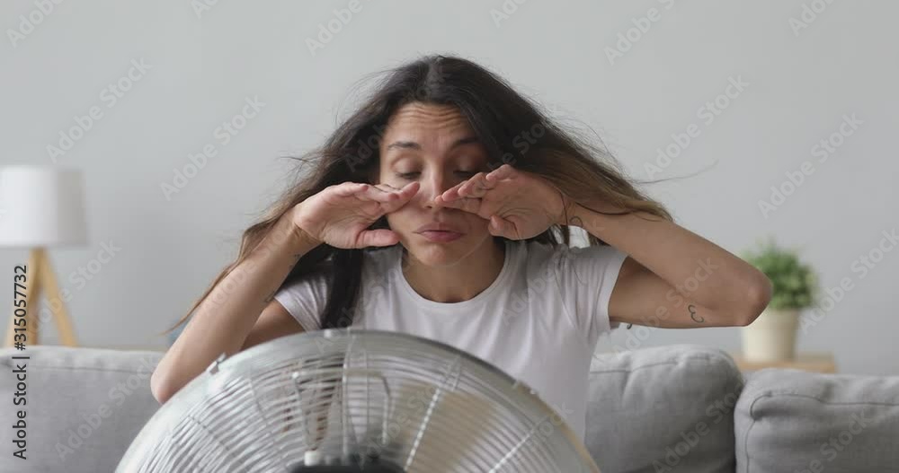 Overheated young mixed race girl sitting in front of ventilator.