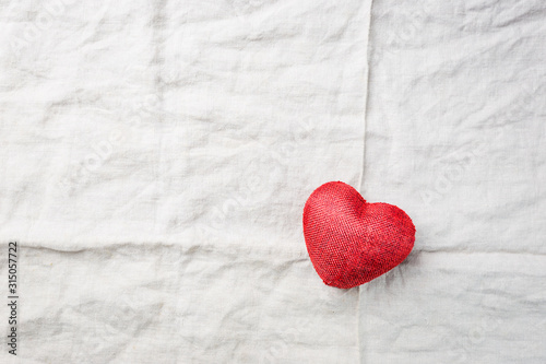 Red fabric heart lie on linen Background  top view with copy space. Valentines Day background.