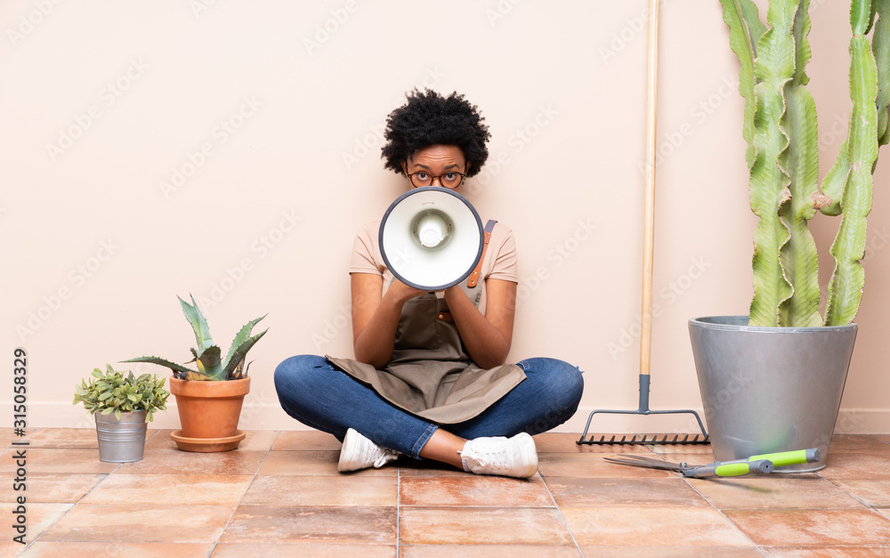 Gardener woman sitting on the floor shouting through a megaphone Gardener woman sitting on the floor shouting through a megaphone