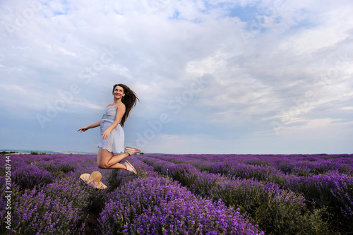 lateral view of a woman in white dress and a hat jumping in the lavander field