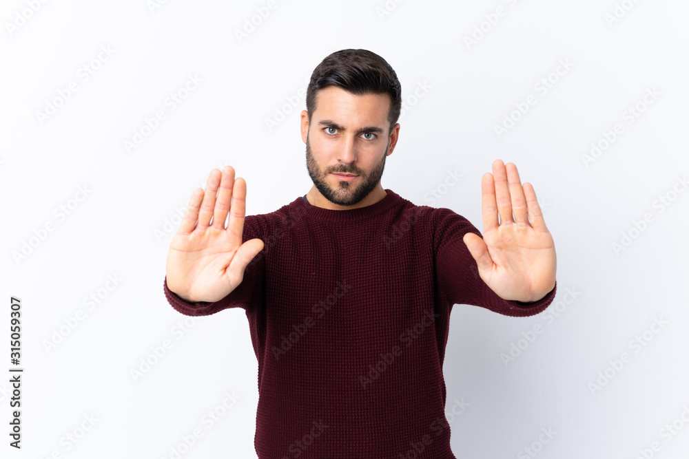 Young handsome man with beard over isolated white background making stop gesture and disappointed Young handsome man with beard over isolated white background making stop gesture and disappointed