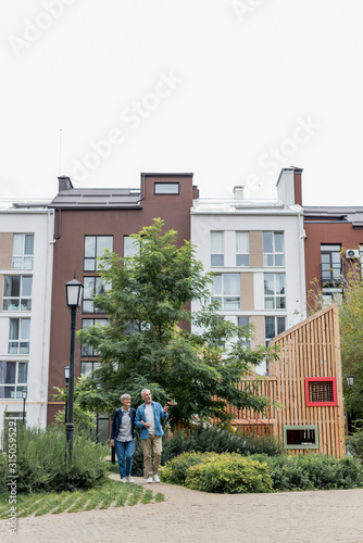 mature man and woman walking near new buildings outside